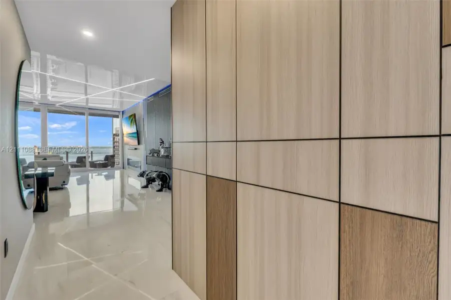 Floor-to-ceiling multi-tonal wood-finish paneling with integrated reveals, polished stone-finish flooring, and expansive floor-to-ceiling glass sliding doors Floor-to-ceiling multi-tonal wood-finish paneling with integrated reveals, polished stone-finish flooring, and expansive floor-to-ceiling glass sliding doors