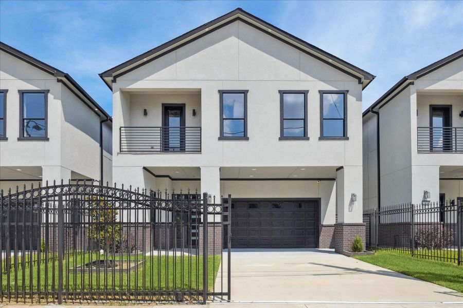 Modern design defines this gated residence, with a streamlined façade and crisp architectural lines. A private driveway and attached garage add ease and seclusion, while the second-level balcony and tall windows fill the interiors with natural light.