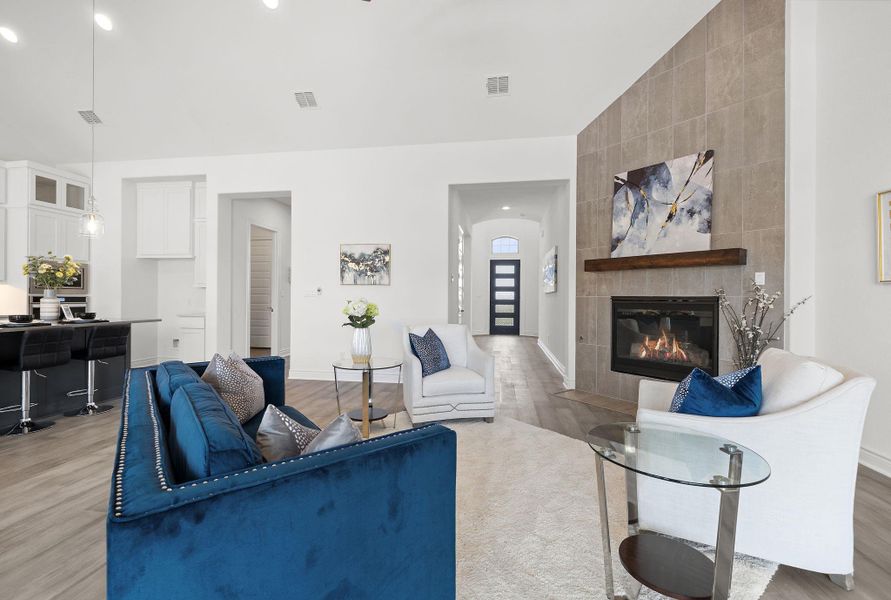 Living room with recessed lighting, light wood finished floors, a tile fireplace, and lofted ceiling