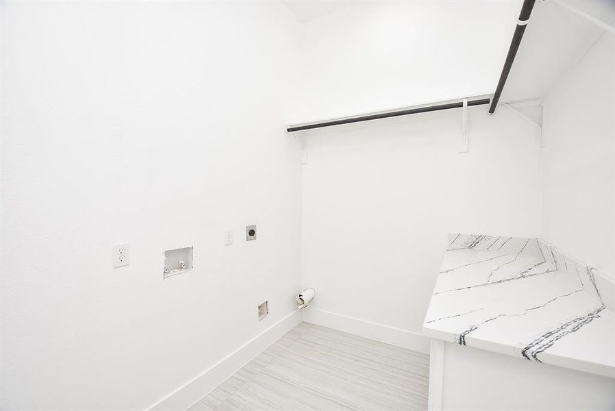 This well-appointed laundry room offers ample storage with built-in cabinets and drawers, plus a spacious quartz countertop for easy folding. A functional and stylish space designed for convenience.