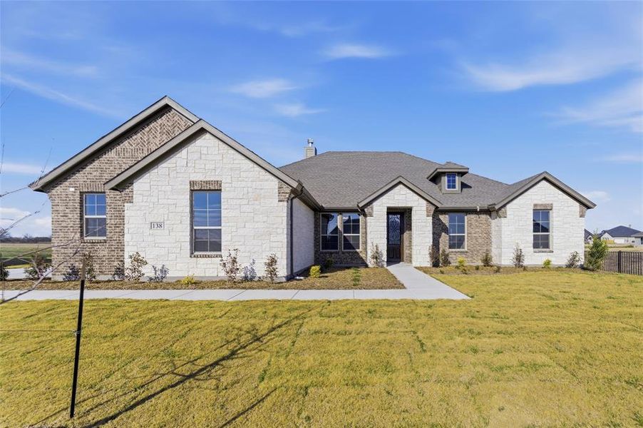 View of front of home with stone siding, a front lawn, and a chimney