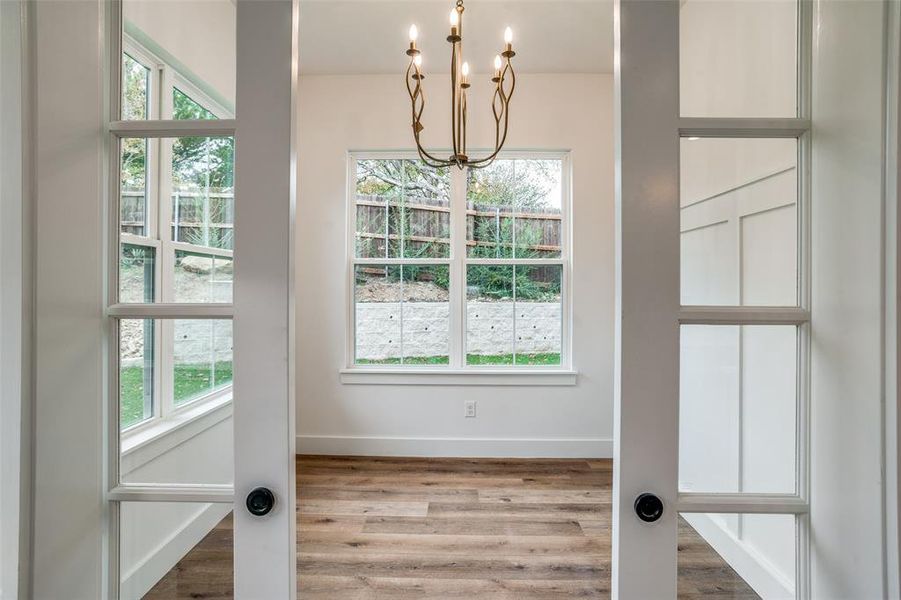 Doorway to outside with hardwood / wood-style floors, a wealth of natural light, and a notable chandelier