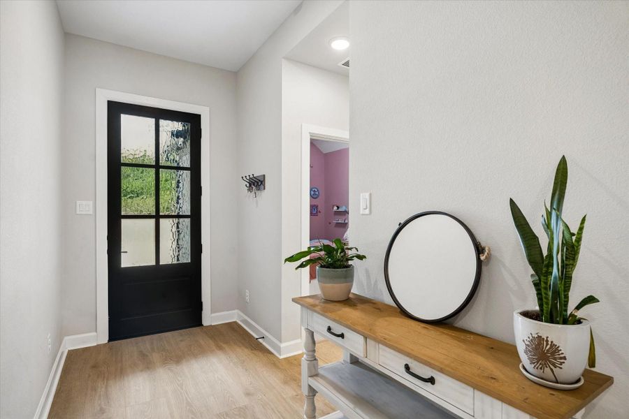 A warm and inviting entry foyer showcases soaring ceilings, rich wood-look flooring, designer lighting, and a stylish modern aesthetic that carries throughout the home. A warm and inviting entry foyer showcases soaring ceilings, rich wood-look flooring, designer lighting, and a stylish modern aesthetic that carries throughout the home.