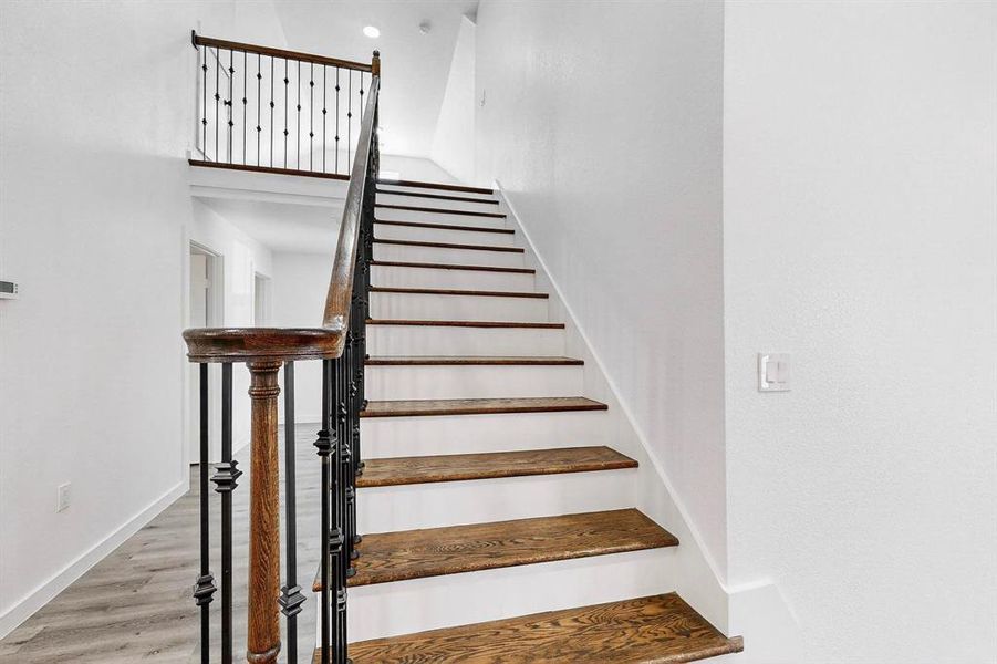 Stairway with wood finished floors and a high ceiling