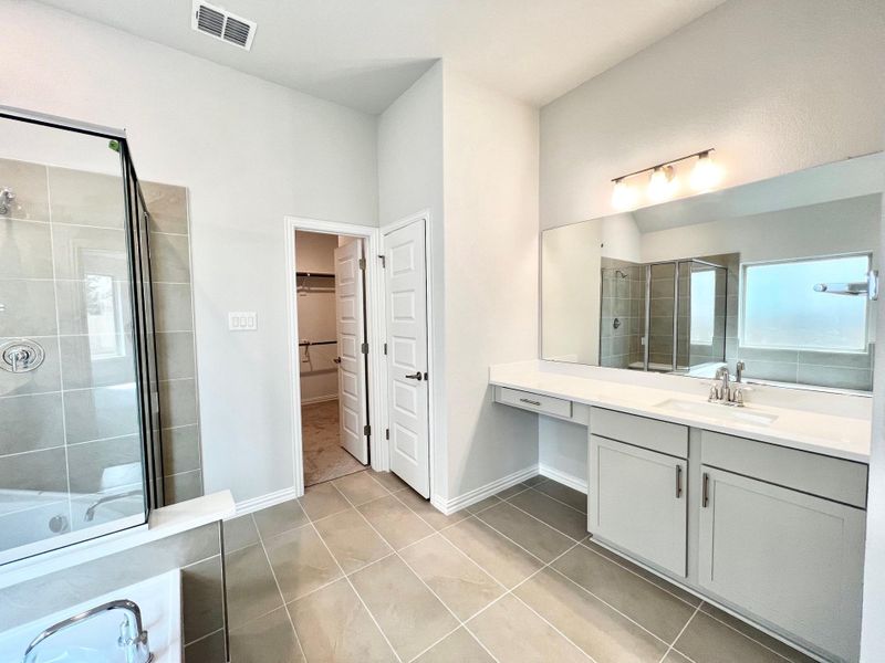 Full bathroom with a stall shower, a spacious closet, vanity, and light tile patterned floors Full bathroom with a stall shower, a spacious closet, vanity, and light tile patterned floors
