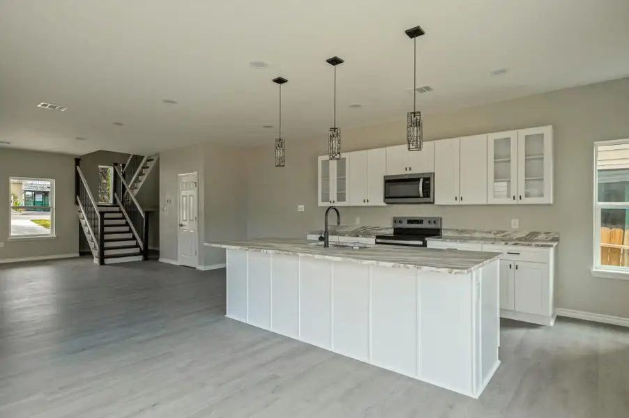 Kitchen featuring glass insert cabinets, appliances with stainless steel finishes, light stone counters, and white cabinetry