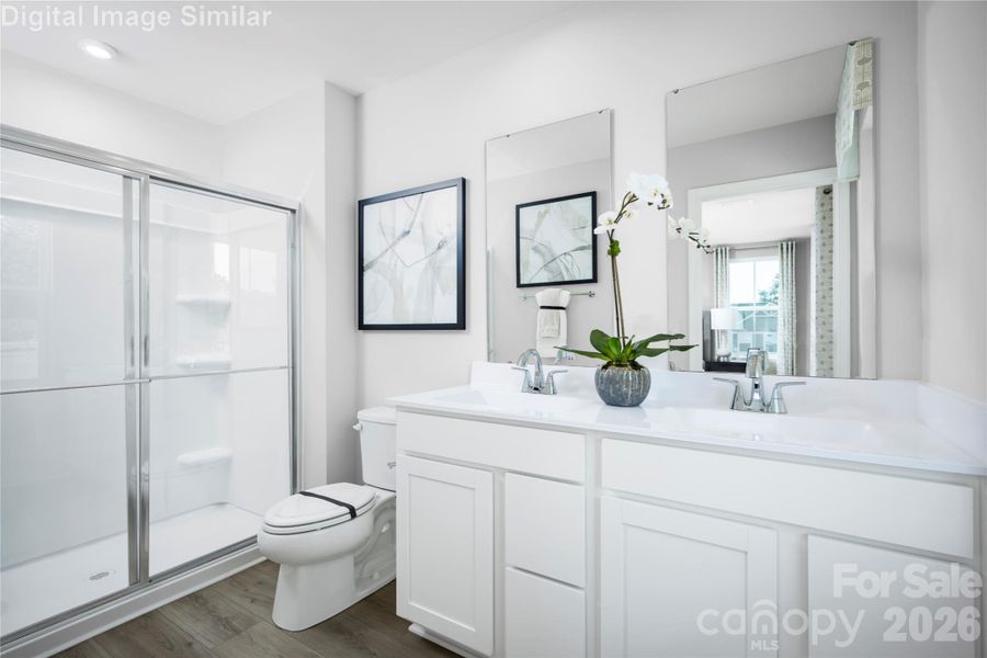 A beautiful ensuite with his-and-hers mirrors, dual sinks, and a sleek framed shower.