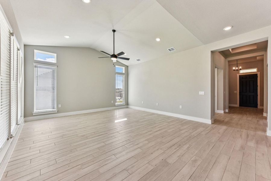 Empty room with light wood-style floors, recessed lighting, vaulted ceiling, and a chandelier
