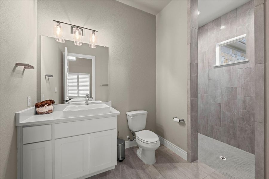 A contemporary bathroom features a clean-lined vanity and a spacious walk-in shower with tiled walls and flooring. A contemporary bathroom features a clean-lined vanity and a spacious walk-in shower with tiled walls and flooring.
