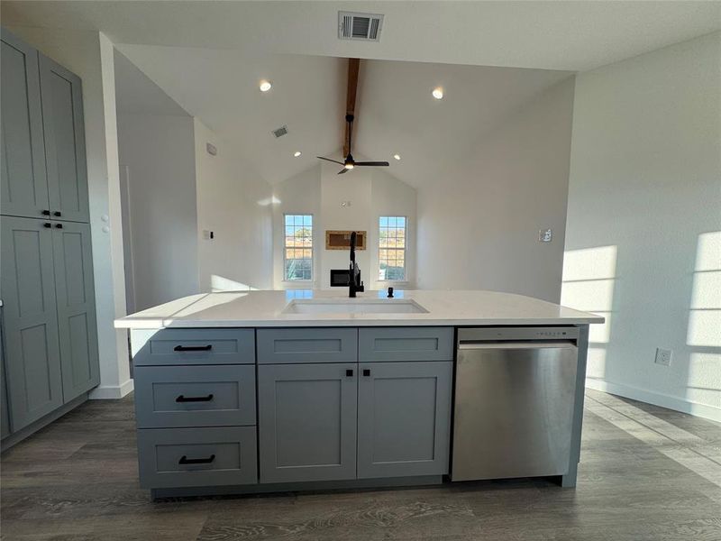 Kitchen featuring gray cabinetry, sink, stainless steel dishwasher, wood-type flooring, and a kitchen island with sink