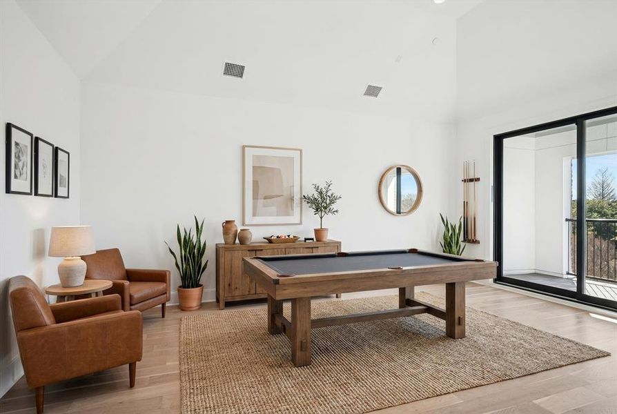 Spacious room featuring vaulted ceilings, light wood-finish flooring, a large sliding glass door, and a private balcony with metal railings Spacious room featuring vaulted ceilings, light wood-finish flooring, a large sliding glass door, and a private balcony with metal railings