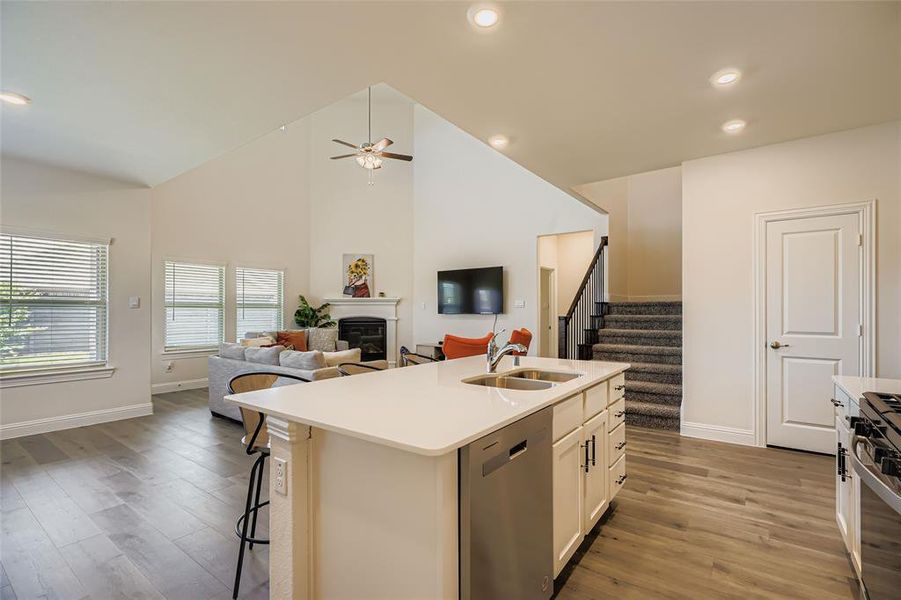 Kitchen with a glass covered fireplace, open floor plan, dark wood-style flooring, appliances with stainless steel finishes, and white cabinetry