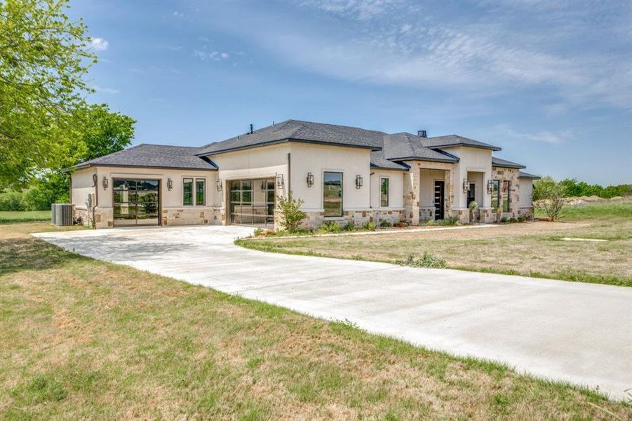 Prairie-style home with central air condition unit, stucco siding, and stone siding