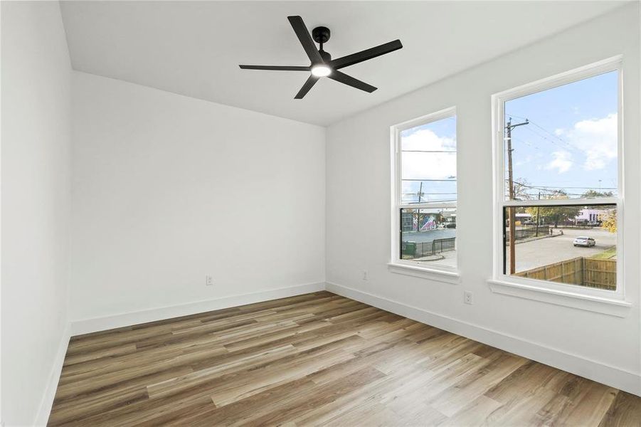Bright room featuring wood-finish flooring, white walls, and a modern ceiling fan