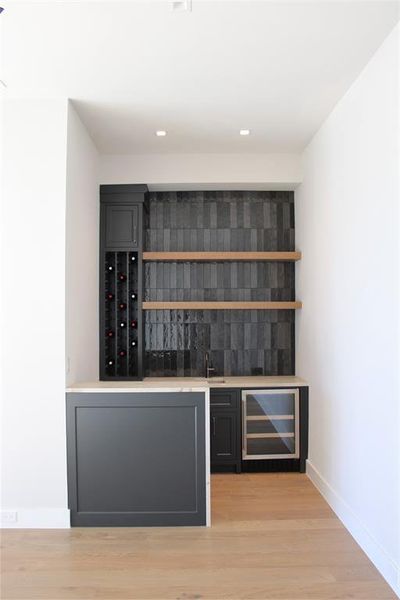 Bar featuring light hardwood / wood-style flooring and beverage cooler