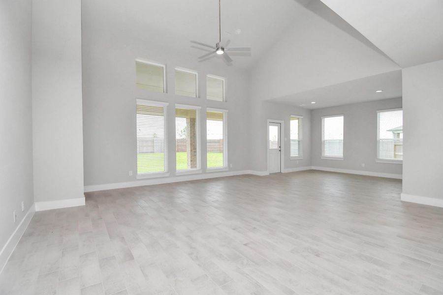 Gather your loved ones in the welcoming living room, a perfect retreat for all seasons. Adorned with lofty high ceilings, recessed lighting, a stylish ceiling fan, custom paint, stunning tile flooring, and expansive windows, this space is bathed in natural light throughout the day. Sample photo of completed home with similar floor plan. Actual colors and selections may vary. Gather your loved ones in the welcoming living room, a perfect retreat for all seasons. Adorned with lofty high ceilings, recessed lighting, a stylish ceiling fan, custom paint, stunning tile flooring, and expansive windows, this space is bathed in natural light throughout the day. Sample photo of completed home with similar floor plan. Actual colors and selections may vary.