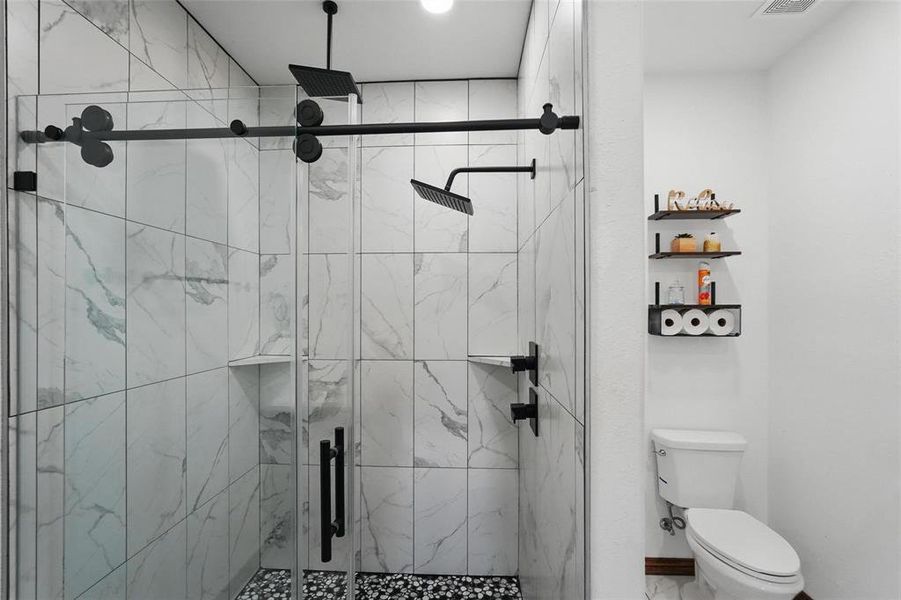 Full bathroom with a marble finish shower and toilet Full bathroom with a marble finish shower and toilet