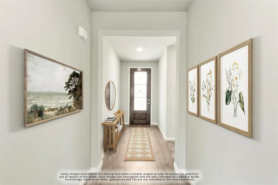Entryway hallway with wood floors, framed wall art, console table, and glass-panel front door