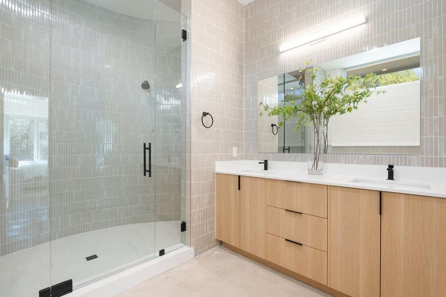 Bathroom with double vanity, tile walls, and a stall shower