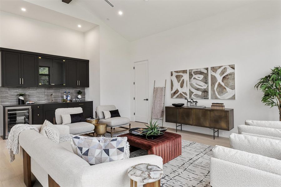 Living area featuring light wood finished floors, wet bar, recessed lighting, high vaulted ceiling, and beverage cooler Living area featuring light wood finished floors, wet bar, recessed lighting, high vaulted ceiling, and beverage cooler