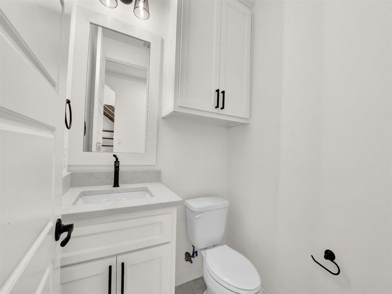 Bathroom featuring toilet, vanity, and baseboards