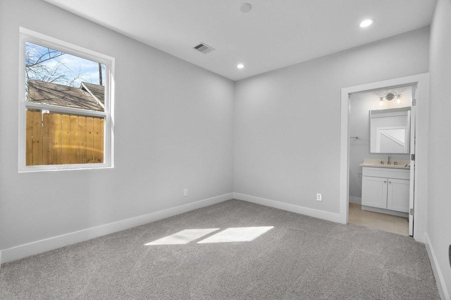 Spacious first floor bedroom with plush carpeting, recessed lighting, and an en-suite bath for added comfort and privacy.