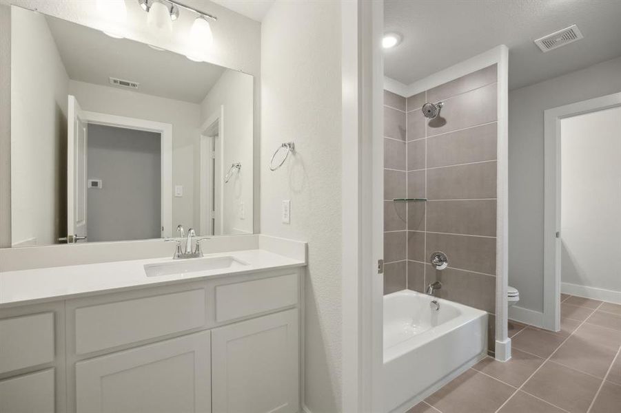 Bathroom with tile patterned flooring, tiled shower / bath, and vanity