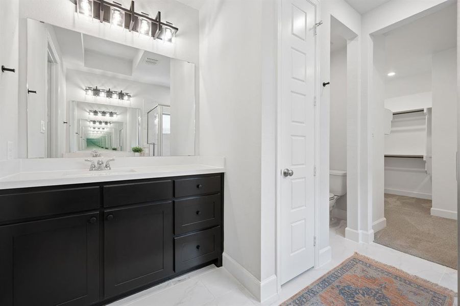 Bathroom vanity featuring dark cabinetry with brushed nickel hardware, a white countertop, and a rectangular mirror