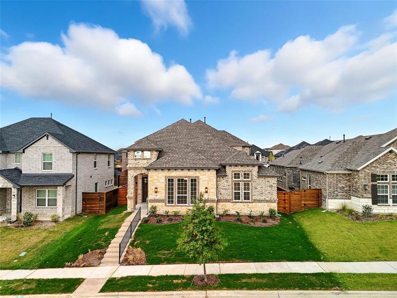 French provincial home with a shingled roof, stone siding, and brick siding