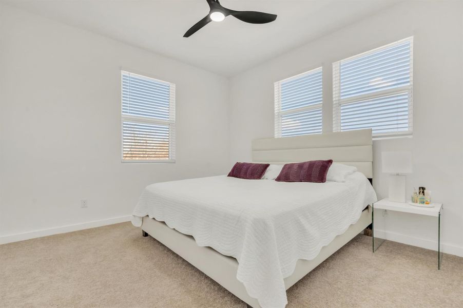 Bedroom with ceiling fan and light carpet