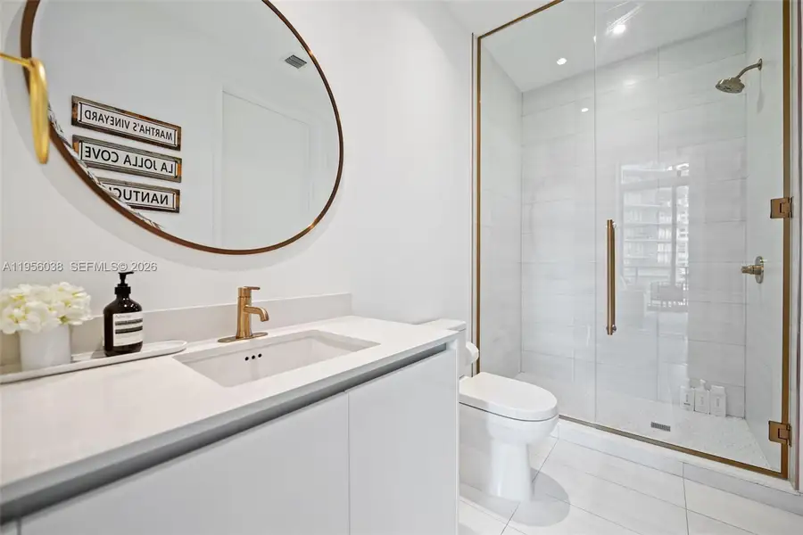 Well-appointed second bathroom offering modern finishes, ample storage, and glass-enclosed shower.