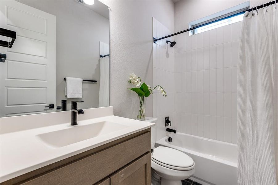 Bathroom with toilet, shower / bath combination with curtain, and vanity