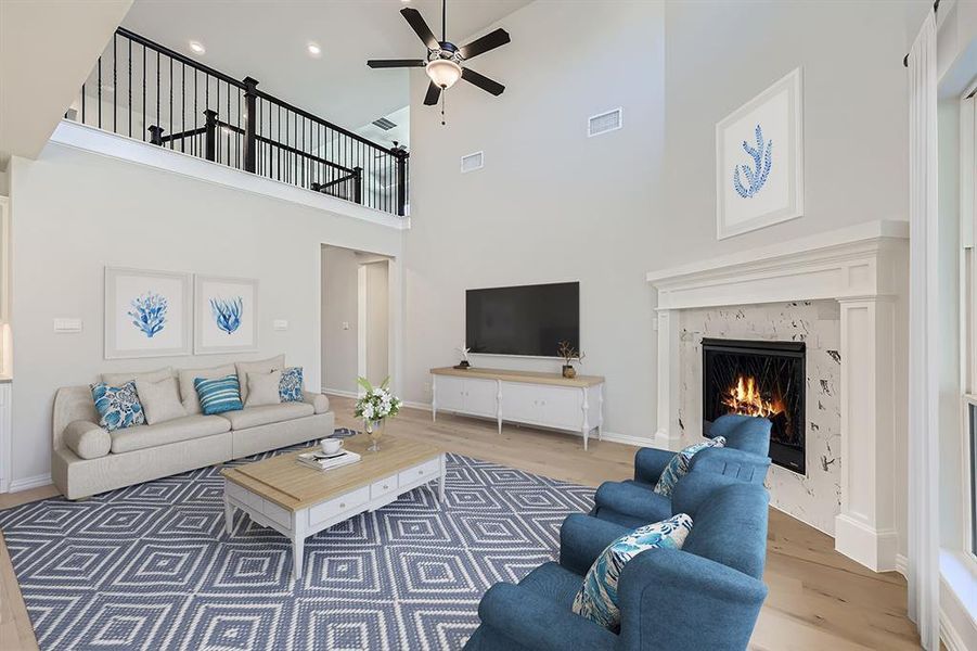 VIRTUALLY STAGED PHOTO -Living room with a premium fireplace, ceiling fan, wood-type flooring, and a high ceiling