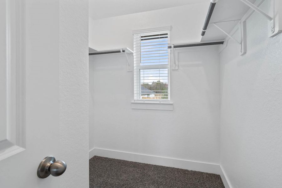 The primary suite features a generous second walk-in closet, illuminated by natural light from a central window and equipped with functional hanging rods and shelving. The primary suite features a generous second walk-in closet, illuminated by natural light from a central window and equipped with functional hanging rods and shelving.