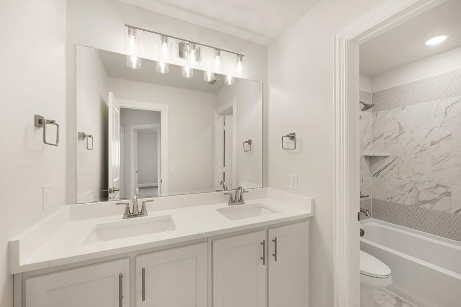 Bathroom with double sink vanity, white cabinets, and marble tile tub surround with separate shower area