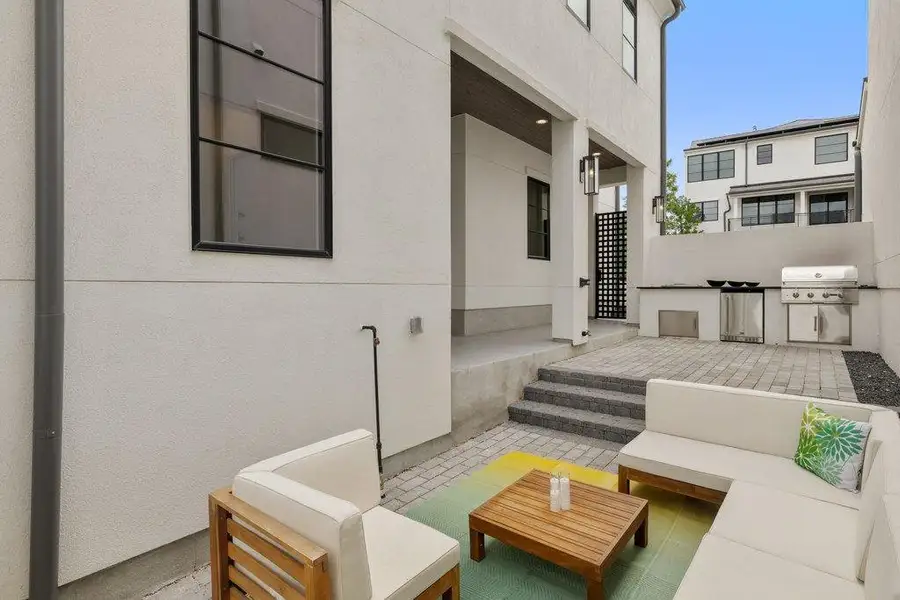 Outdoor patio with a built-in grill station, paved hardscaping, exterior sconce lighting, and a covered porch area