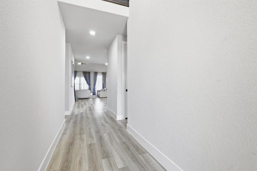 Hall with light wood-style flooring, recessed lighting, and a textured wall