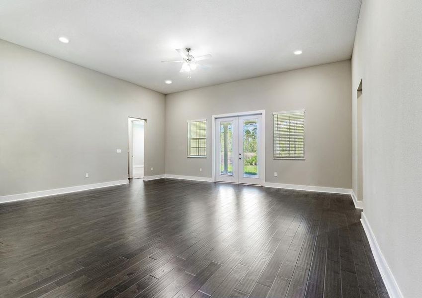 Living room with wood flooring and double doors that lead to the covered outdoor kitchen.