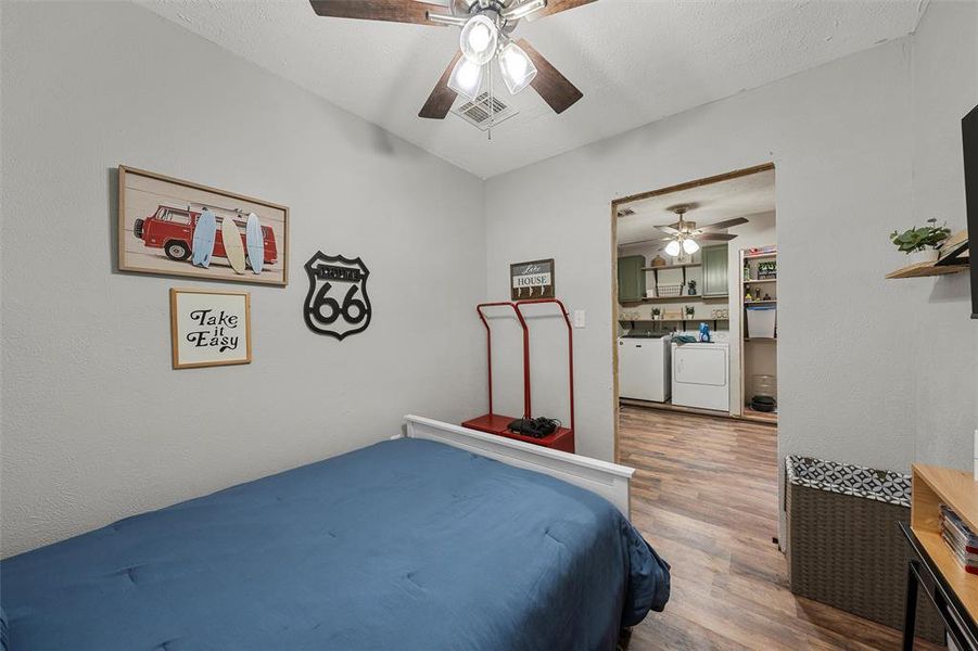 Bedroom with washer and dryer, wood finished floors, and ceiling fan Bedroom with washer and dryer, wood finished floors, and ceiling fan