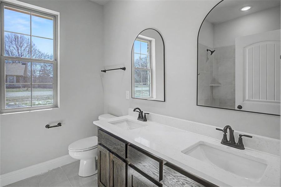 Full bath featuring double vanity, light tile patterned floors, and tiled shower