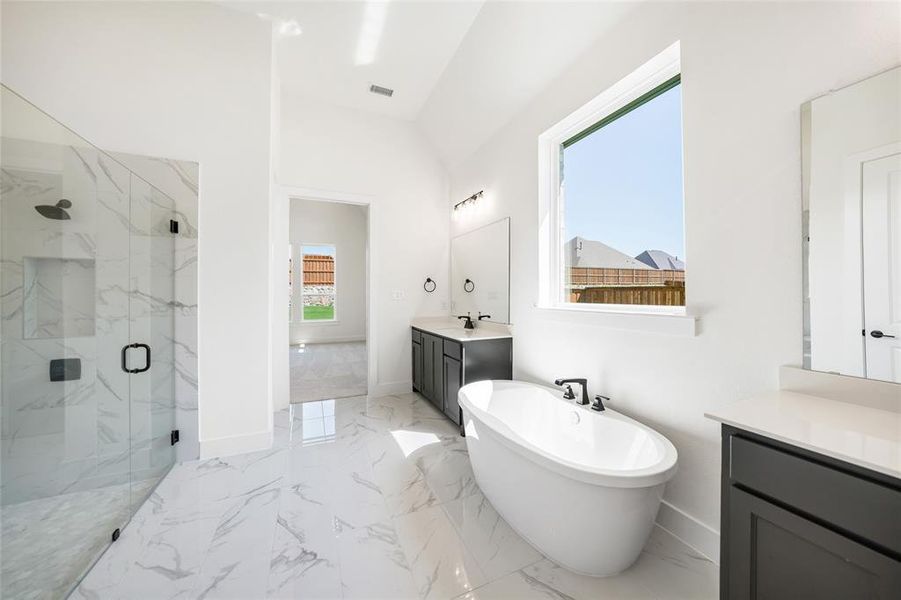 Full bathroom featuring a marble finish shower, a freestanding tub, vanity, and light marble finish flooring