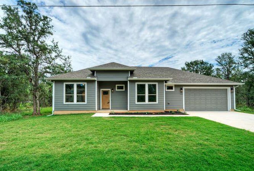 View of front of home featuring concrete driveway, a garage, a front yard, and roof with shingles