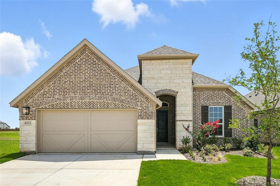 French country style house with a garage, brick siding, concrete driveway, and roof with shingles