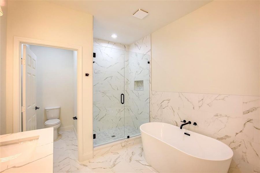 Full bath with a marble finish shower, a freestanding bath, marble finish flooring, recessed lighting, and tile walls Full bath with a marble finish shower, a freestanding bath, marble finish flooring, recessed lighting, and tile walls