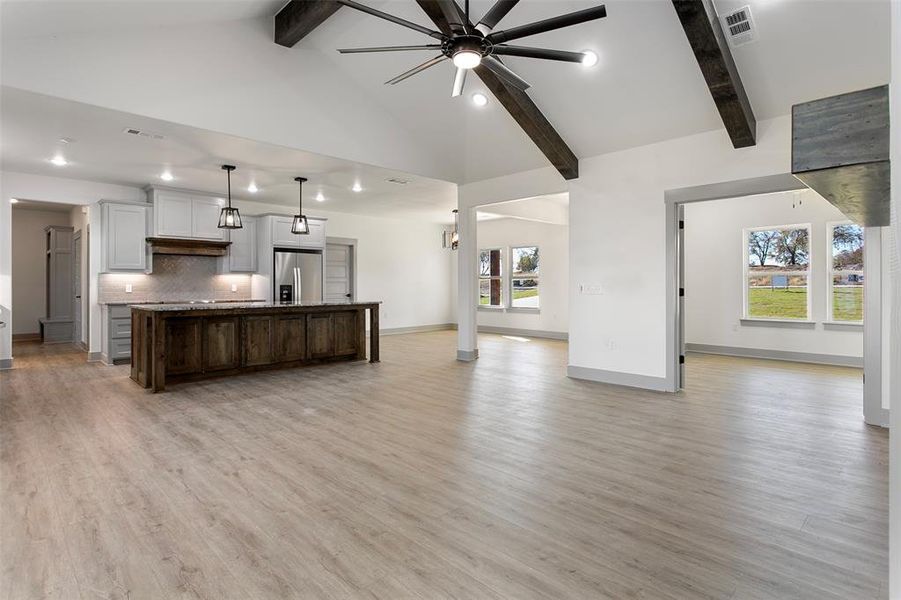 Kitchen with stainless steel fridge, a center island with sink, a wealth of natural light, and light hardwood / wood-style floors