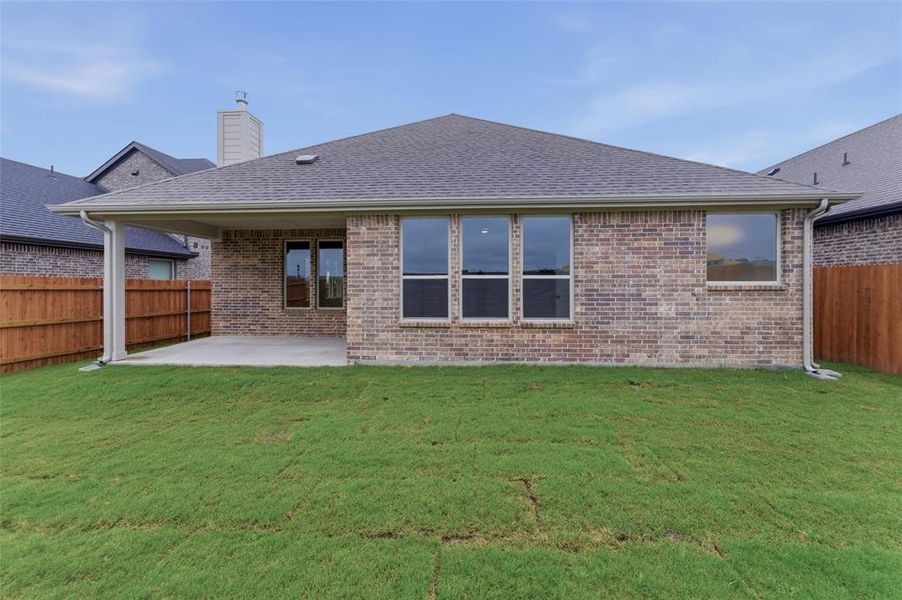 Rear exterior featuring a covered patio, brick facade, and a wood privacy fence