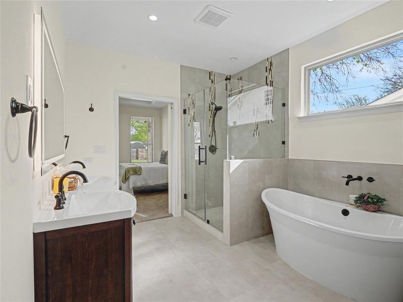 Full bathroom featuring a stall shower, double vanity, a freestanding tub, ensuite bathroom, and recessed lighting