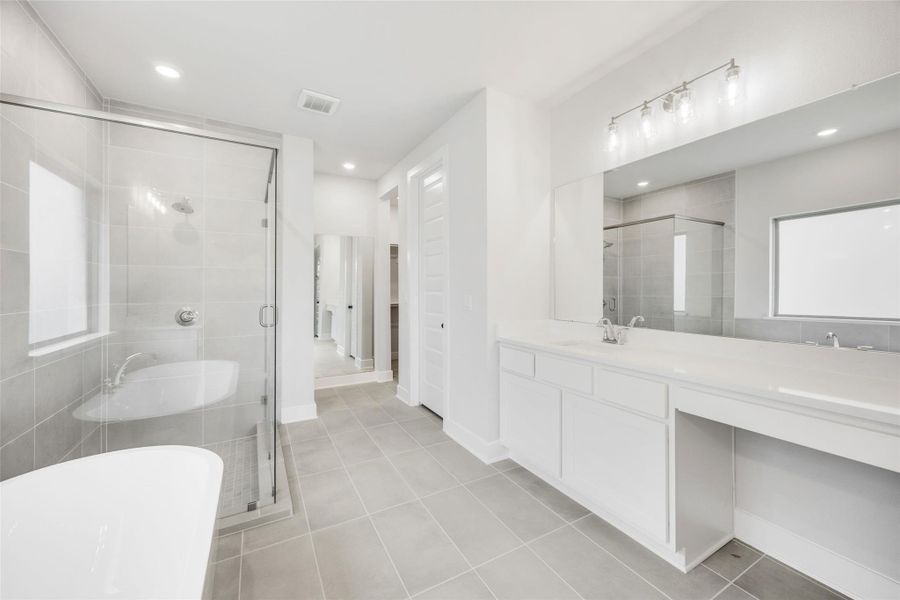 Bathroom featuring vanity, a freestanding tub, light tile patterned floors, a shower stall, and recessed lighting Bathroom featuring vanity, a freestanding tub, light tile patterned floors, a shower stall, and recessed lighting