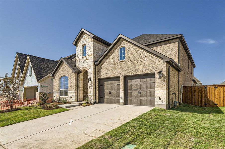 French country inspired facade with a front lawn and a garage