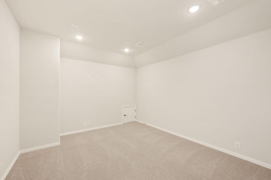 Empty room with white walls, beige carpet, recessed lighting, and a small door